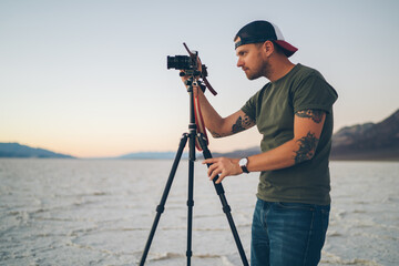 Male traveler photographing sunset in waterless terrain