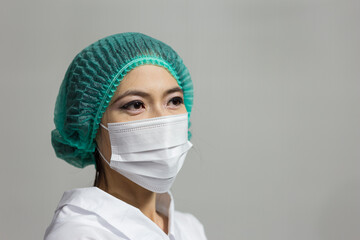Woman doctor wearing protective mask standing isolated on gray background