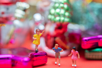 Miniature people with new year and Christmas holiday ornament and presents box in background. Holiday shopping concept