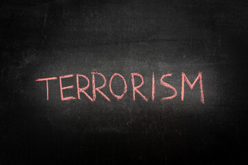 The word TERRORISM in red chalk on a black chalkboard