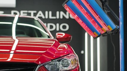 Red lamps for drying the ceramic coating are behind car