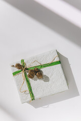 present gift box wrapped with white paper and green ribbon
