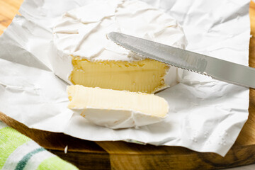 Round piece of camembert cheese on a wooden background.