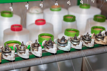 Red-green spools of white yarn in a garment factory. Weaving loom in a textile factory.