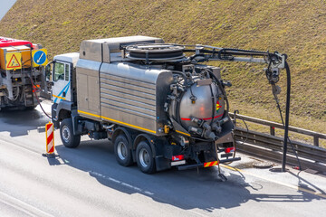 Sludge washer truck suction machine and workers specialists at work on the side of the highway to...