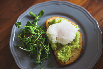 Full healthy morning breakfast: toast with guacamole, avocado, poached egg and flaxseed.