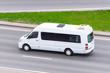 White minibus goes on the city highway street.