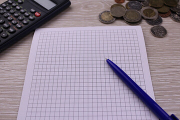 Checkered notebook with calculator and coins for background