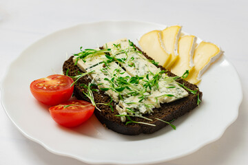 Rye bread with blue cheese and sprouted grains on a plate.