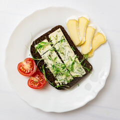 Rye bread with blue cheese and sprouted grains on a plate on a white background.