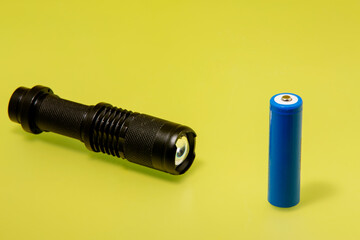 Black Electric LED Flashlight Powered by Rechargeable Battery in yellow Isolated Background
