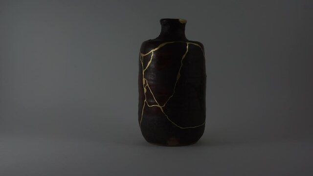 Kintsugi bizen sake bottle. Bright gold cracks lighted up. Fragile cracks trauma representation. Psycology.