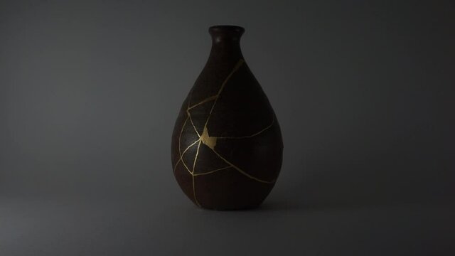 Kintsugi bizen sake bottle. Bright gold cracks lighted up. Fragile cracks trauma representation. Psycology.