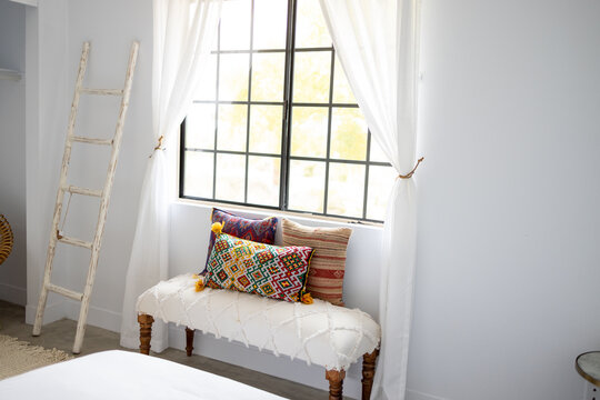 Southwestern Style Interior Of A Bedroom With Decorative Pillows And Bench Under A Window