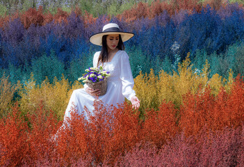 Fototapeta na wymiar Beautiful Thai woman sits among the cutters flower in rainbow colors in Chiang Mai province, Thailand.
