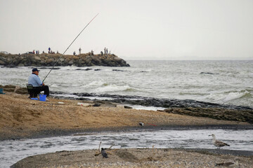 A fisherman with a fishing rod on the shores of the Caspian Sea.