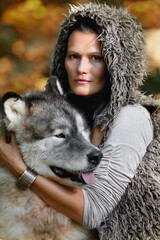 Portrait of a young nice woman with an Alaskan Malamute dog in the autumn forest