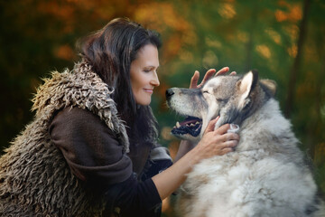 Woman with Alaskan Malamute dog in the autumn forest