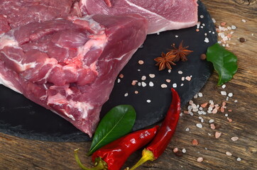 Fresh raw meat on old wooden board with spices. Boneless lamb steak meat