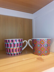 Candles on a shelf.  Two glass colorful candles on a shelf with a white background 