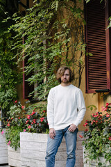 Man wearing white sweatshirt or hoodie for mock up, logo designs or design prints with with free space on the city streets.