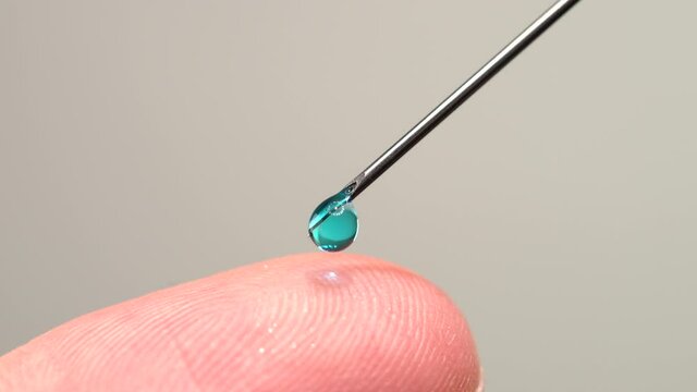 Finger touching medical syringe needle. Macro close up. Trypanophobia, extreme fear of injections or hypodermic needles. Dangerously close hand skin to the sharp needle. Phobias and traumas.