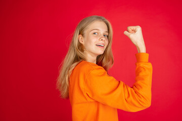 Fototapeta premium Strong, power. Portrait of young caucasian woman isolated on red studio background with copyspace. Beautiful female model. Concept of human emotions, facial expression, sales, ad, youth.