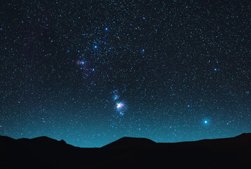 Beautiful Orion Nebula on the starry sky over the hill silhouette. Night photography Astronomical...