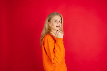 Pointing. Portrait of young caucasian woman isolated on red studio background with copyspace. Beautiful female model. Concept of human emotions, facial expression, sales, advertising, youth.