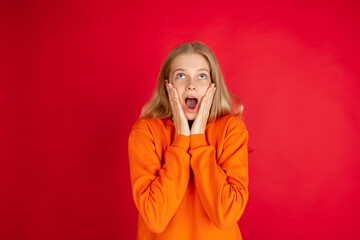 Shocked looking up. Portrait of young caucasian woman isolated on red studio background with copyspace. Beautiful female model. Concept of human emotions, facial expression, sales, ad, youth.