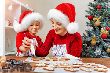 Obraz na płótnie Canvas Mother and daughter prepare Christmas cookies and decorate them with icing for a happy holidays