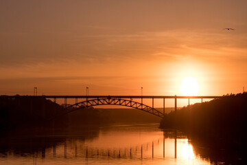 the setting sun against the background of the railway bridge over the river