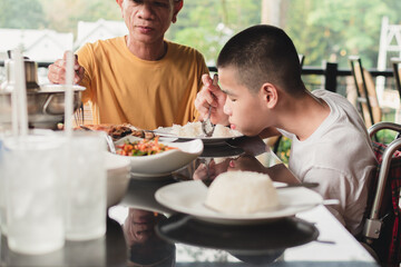 Asian disabled child on wheelchair eating breakfast by themselves,The skills to practice muscle development, Special children's lifestyle, Life in the education age, Happy disability kid concept.