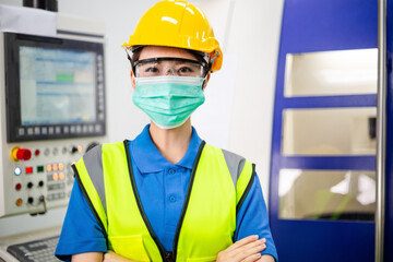 Portrait of Asian worker woman in medical face mask in arms crossed looking at camera in industrial factory. new normal working during coronavirus. healthcare lifestyle for industry people