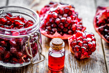 sliced pomegranate and extract in glass on wooden background