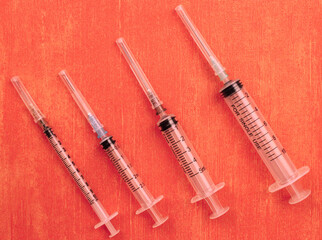 Four syringes on an orange-red background