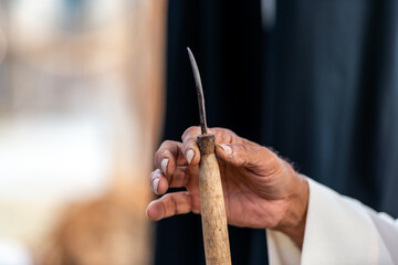 arabian pearl diver showing how to open a shell to find salt wate pearls, an old tradition in the gulf countries such as UAE, focus on the hands of an elderly man 