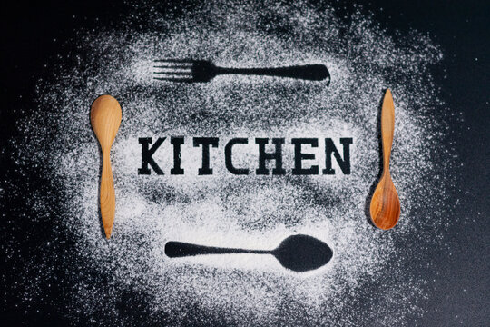 Images of forks and spoons on a white flour background. Two wooden tablespoons. The inscription is a kitchen in the center. 