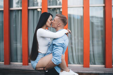 Passion emotion from spouse lovers kissing during prelude at urban setting in city, side view of Caucasian boyfriend holding on arms and touching beautiful girlfriend enjoying feelings relation