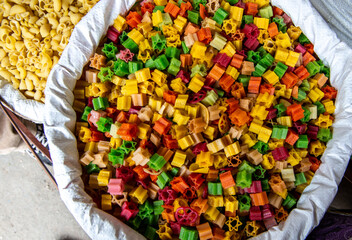 colorful pasta on a market in a big sack, natural colored in many different colors, yellow, green, red  and orange can be used as background or wallpaper 