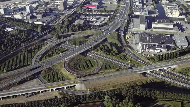 Aerial view of Amsterdam A10 an d A2 motorway interchange on a sunny day. Many trucks, cars and trains passing by. Netherlands. Transportation.