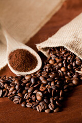 Fototapeta na wymiar coffee powder (ground), on wooden spoon, coffee beans, with raffia cloth bag, brown background
