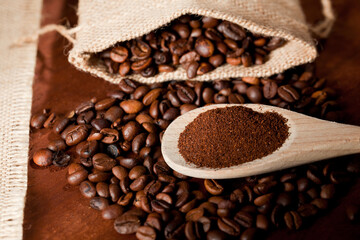 coffee powder (ground), on wooden spoon, coffee beans, with raffia cloth bag, brown background