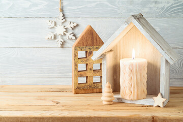 Christmas holiday background with home decor house and candle on wooden table. Winter greeting card.
