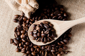 Coffee, on wooden spoon, with raffia cloth bag, brown background