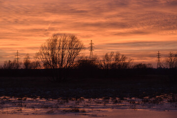 Pillars of a high-voltage power line in the fields in late autumn against the sunset