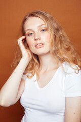 Obraz premium young pretty girl with blond curly hair posing cheerful on brown background, lifestyle people concept