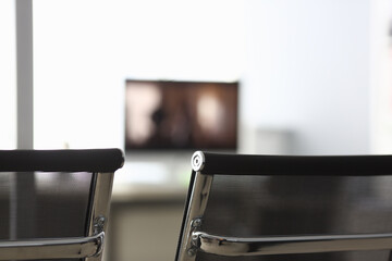 Close-up of room for conversation with black armchairs, computer monitor and other supplies for...