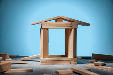 House made of wooden blocks on a blue background and randomly lying blocks