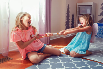 Two little mad angry girls sisters having fight at home. Friends girls can not share a toy. Lifestyle authentic funny family moment of siblings quarrel life. Kids bad behaviour. - obrazy, fototapety, plakaty